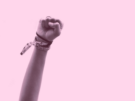 Pink-tinted photo of a clenched fist being raised.